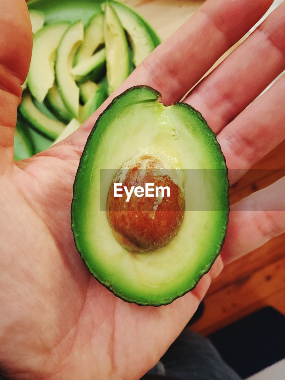 Cropped hand holding halved avocado