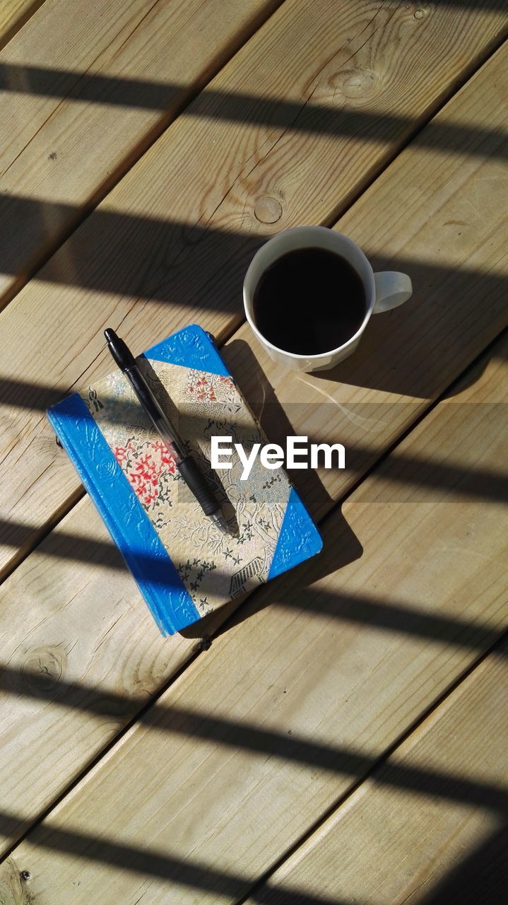 High angle view of coffee by book and pen on table