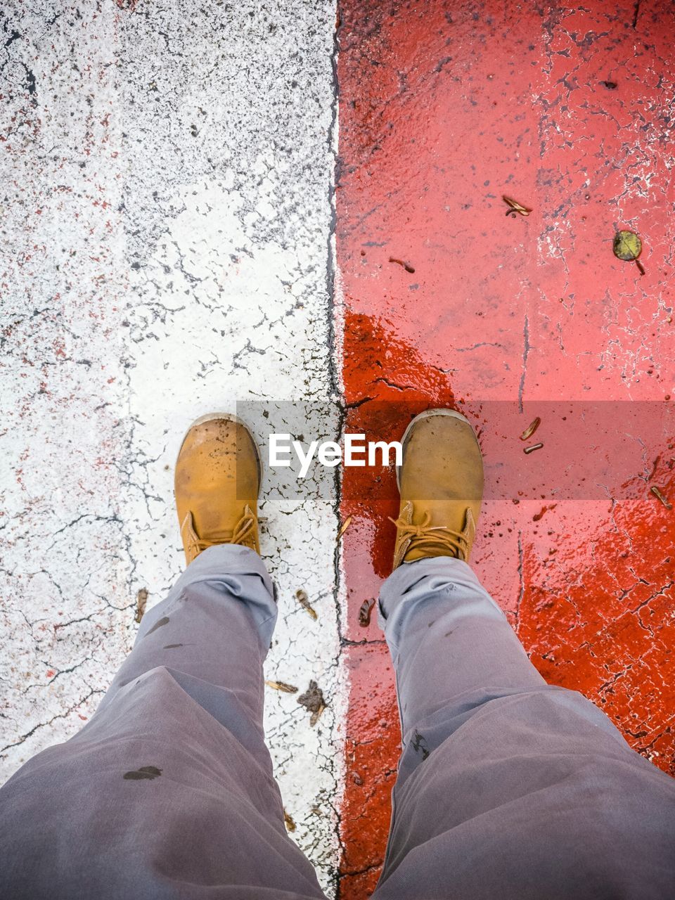 Low section of man standing on wet painted road