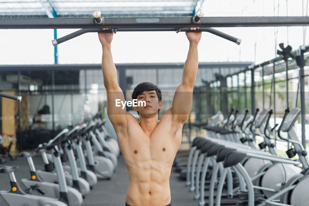 Portrait shirtless man exercising at gym