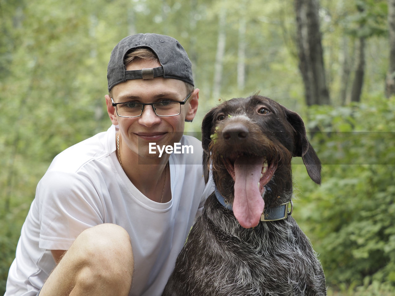 Portrait, a young man of european appearance with a dog in the forest. high quality photo