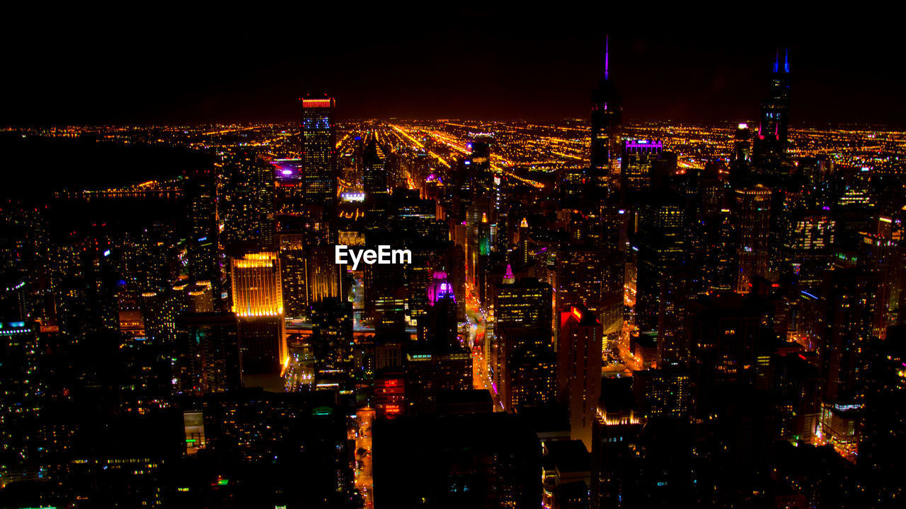 Illuminated cityscape against sky at night