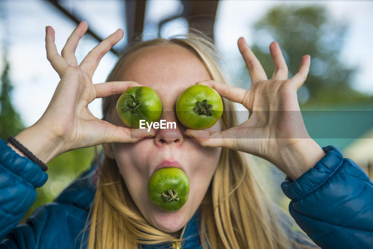 Young woman playing with green tomato