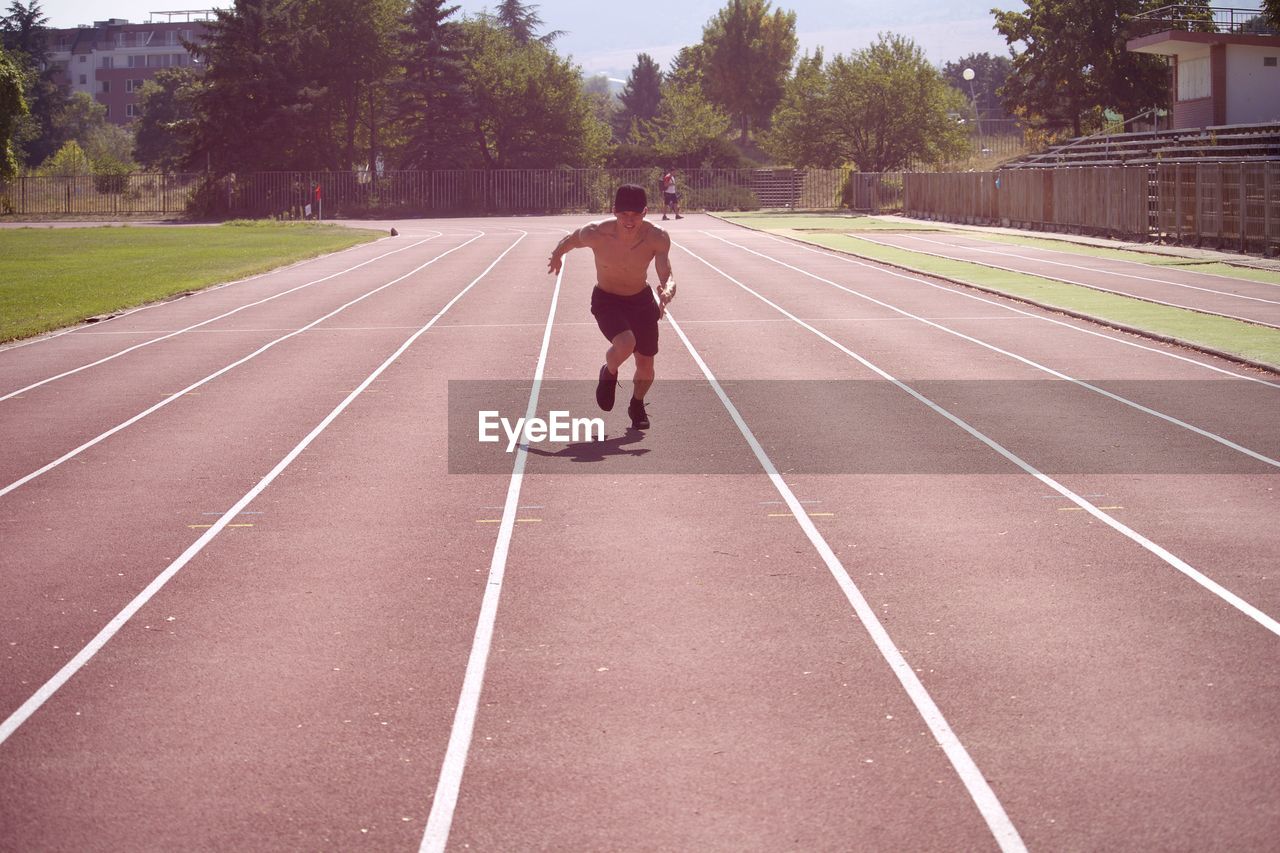 Shirtless man running on track