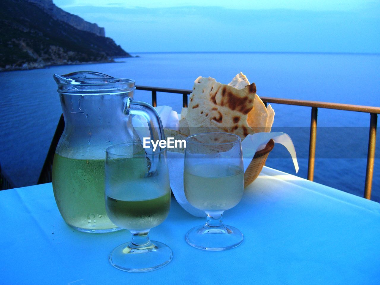 Close-up of alcohol on table by sea during sunset