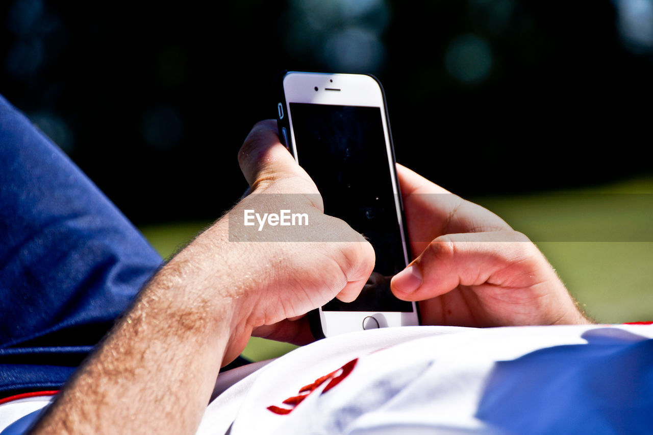 Close-up of man using mobile phone while lying on field