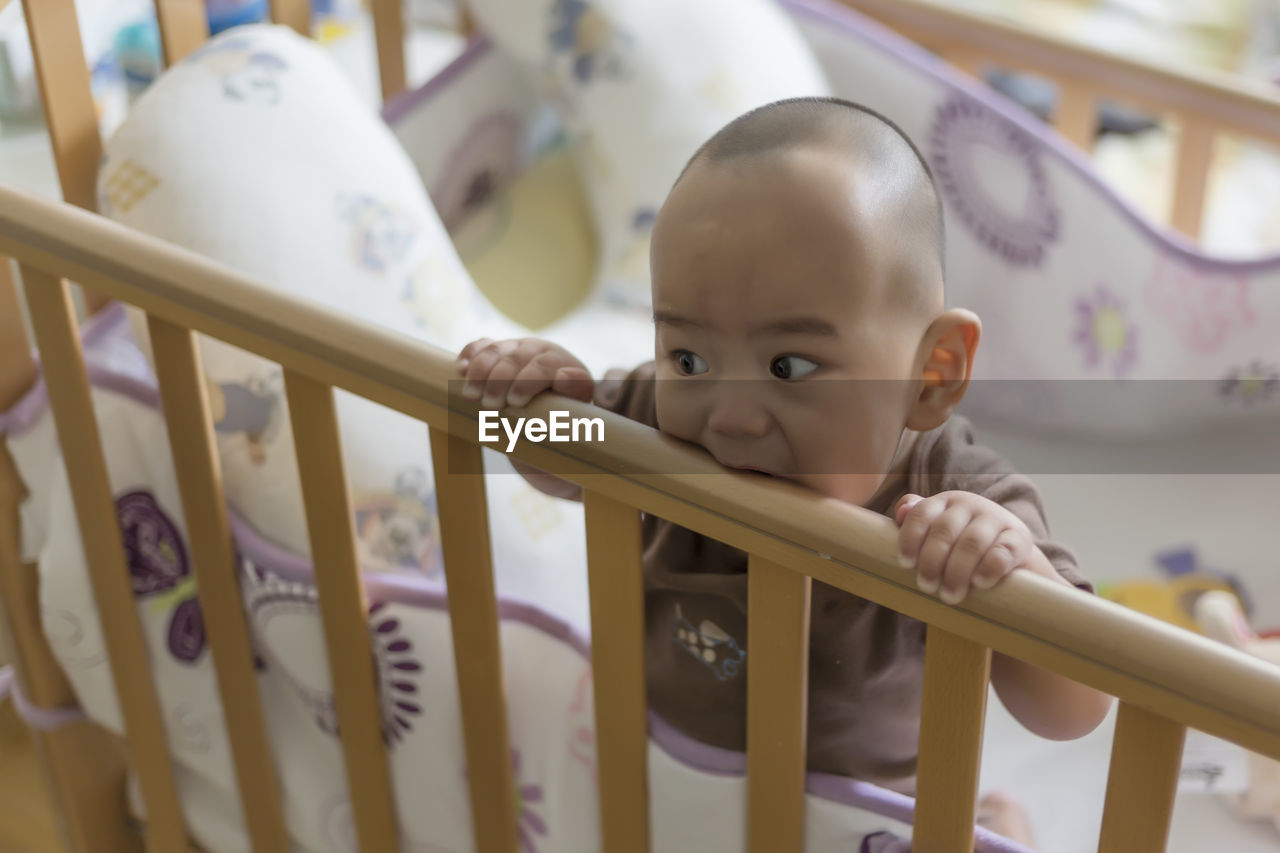 High angle view of cute baby boy sitting in crib