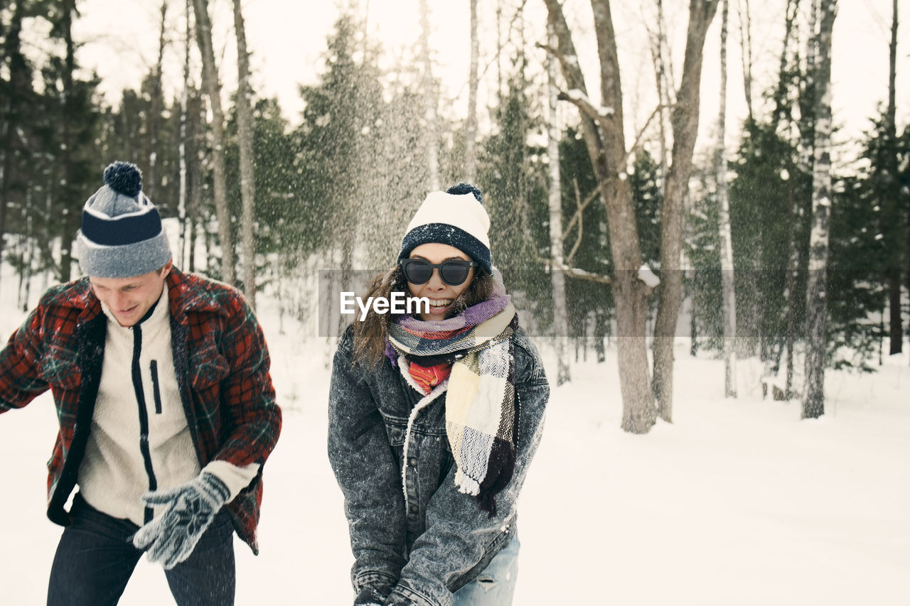 Happy friends playing on snow covered landscape