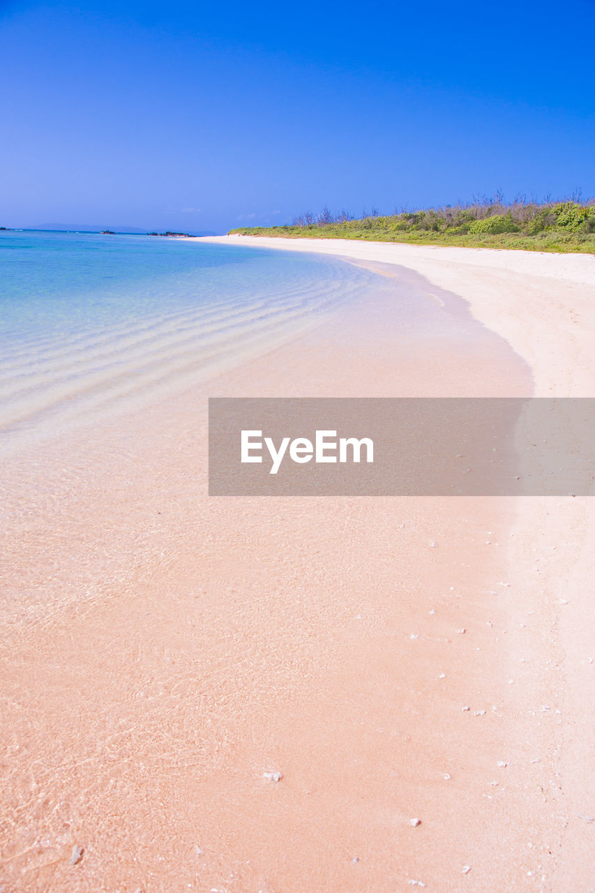 Scenic view of beach against clear blue sky