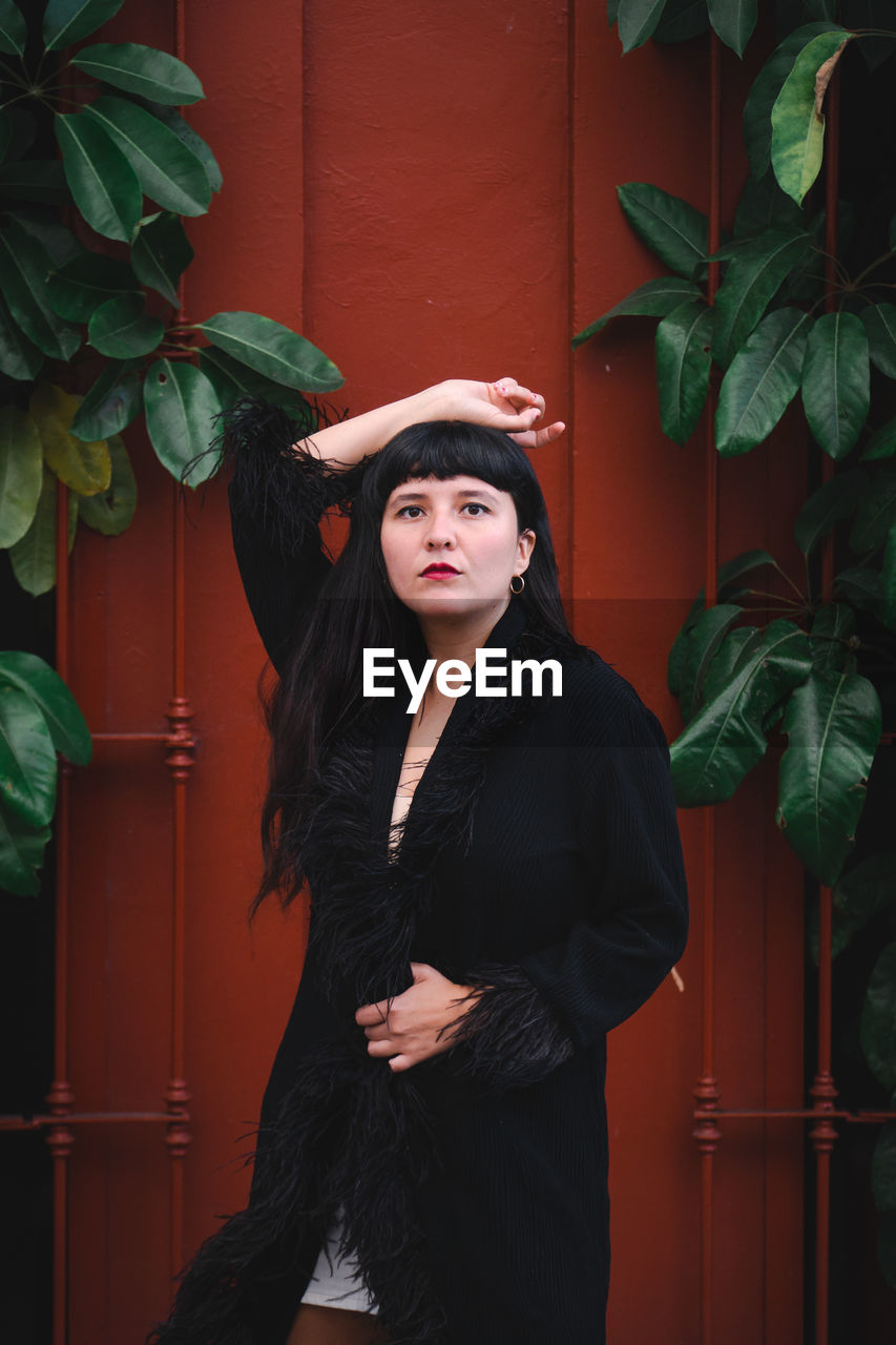 Dark-haired female model in vintage clothing and make-up against a colorful wall.