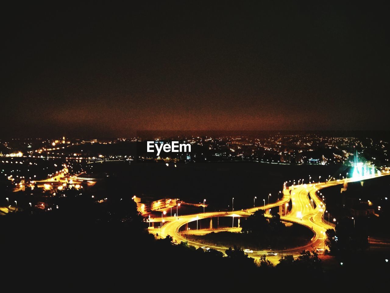 HIGH ANGLE VIEW OF ILLUMINATED BUILDINGS BY RIVER AGAINST SKY