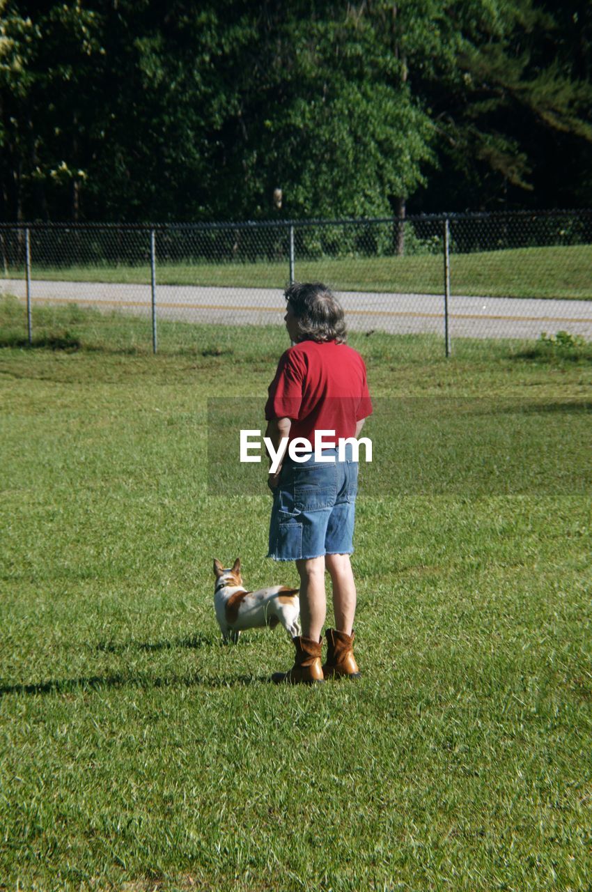 Full length of man with dog standing on grassy field