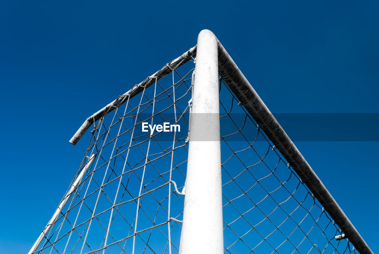 LOW ANGLE VIEW OF CHAINLINK FENCE AGAINST BLUE SKY