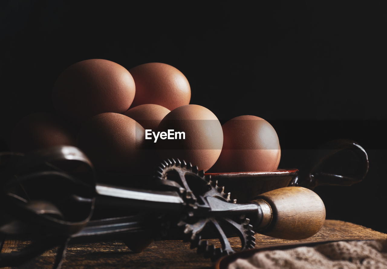 Organic chicken eggs on wood with a iron whisk, dark backround