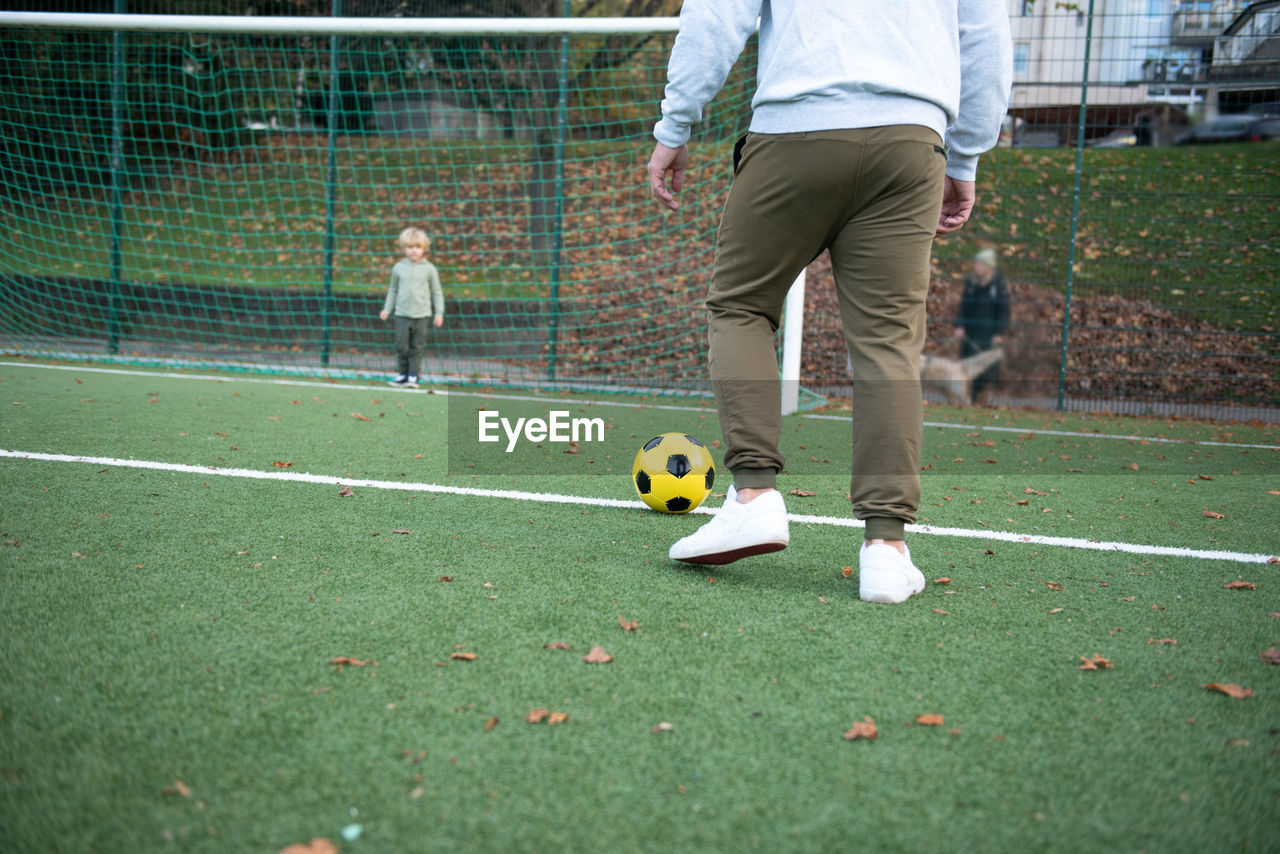 A little boy plays soccer with his father on the soccer field