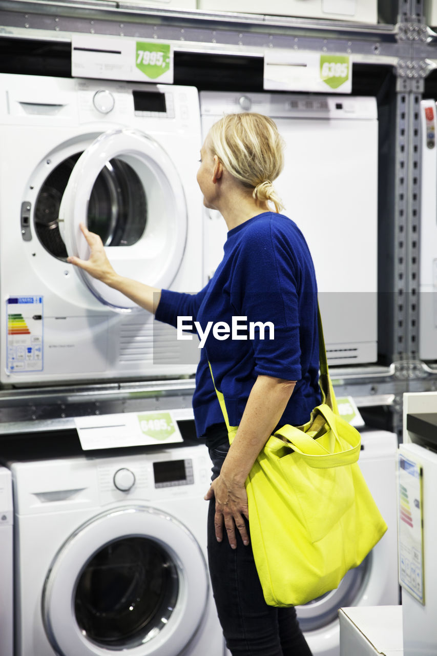 Woman looking at washing machine in shop