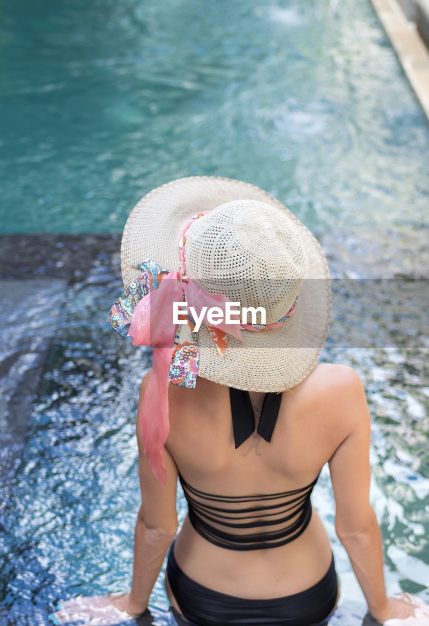 Rear view of woman with hat on swimming pool
