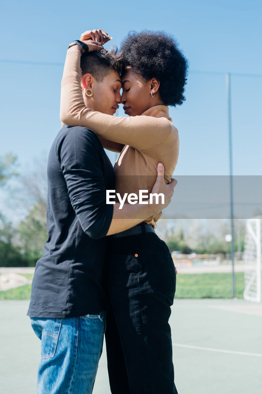 Young couple embracing each other standing at sports court