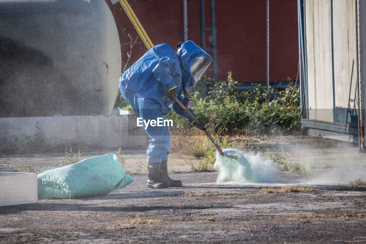 Full length of manual worker adding fertilizer on field