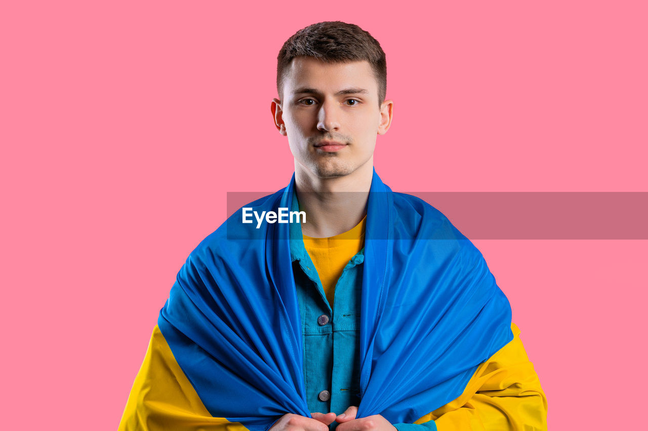 portrait, one person, studio shot, young adult, looking at camera, colored background, adult, indoors, men, yellow, front view, blue, waist up, clothing, person, outerwear, copy space, emotion, sports, serious, sleeve, lifestyles, smiling, standing, athlete, pink, casual clothing