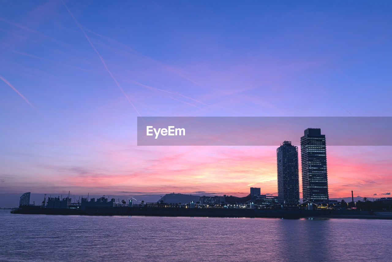 Sea and buildings against sky during sunset