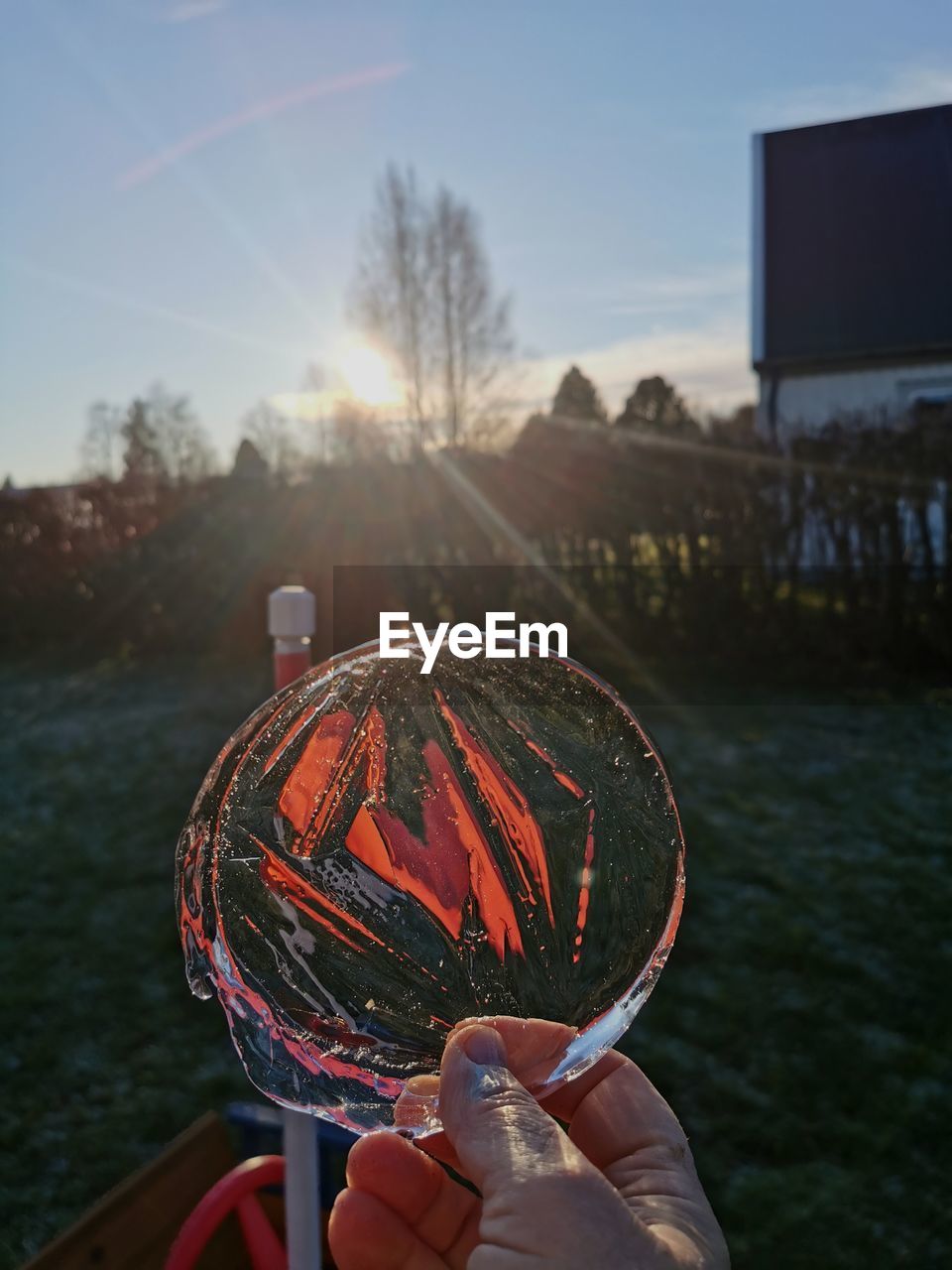 CLOSE-UP OF PERSON HOLDING ICE CREAM AGAINST SKY