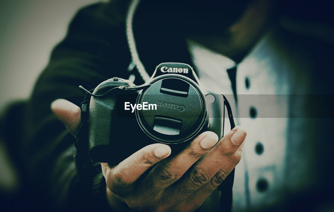 CLOSE-UP OF MAN HOLDING CAMERA