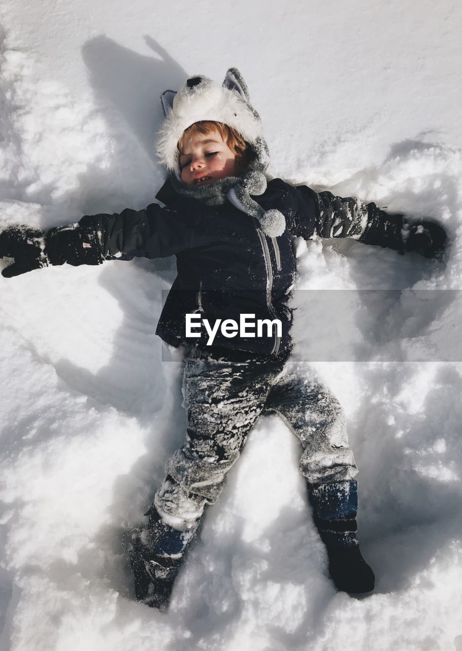 Boy lying on snowy field