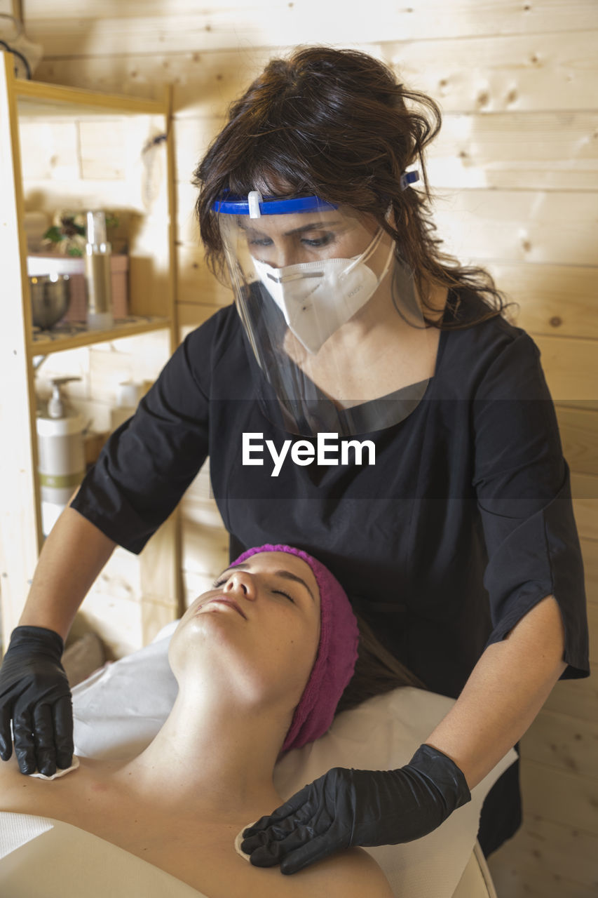 Beautician working with mask and protective screen for the virus covid