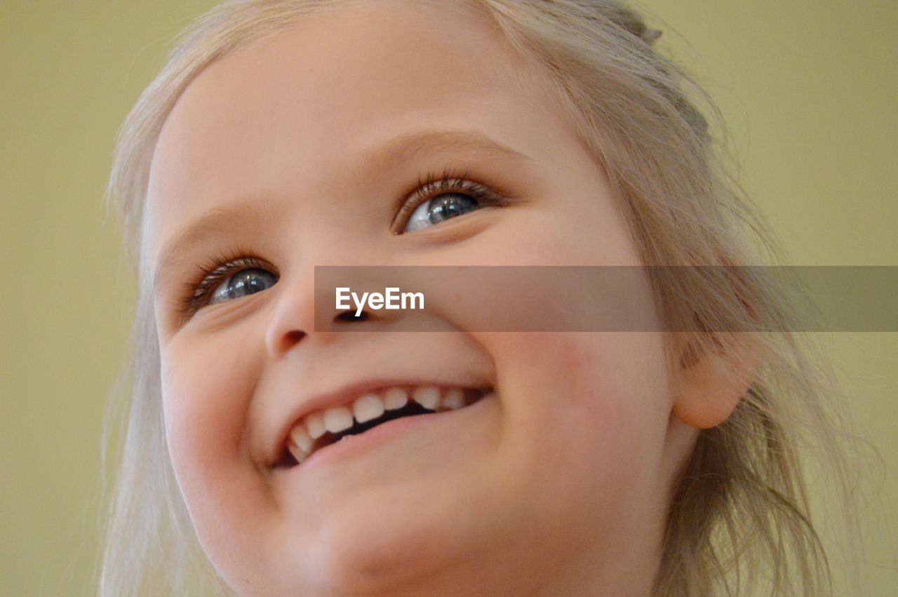 Close-up of smiling girl against colored background