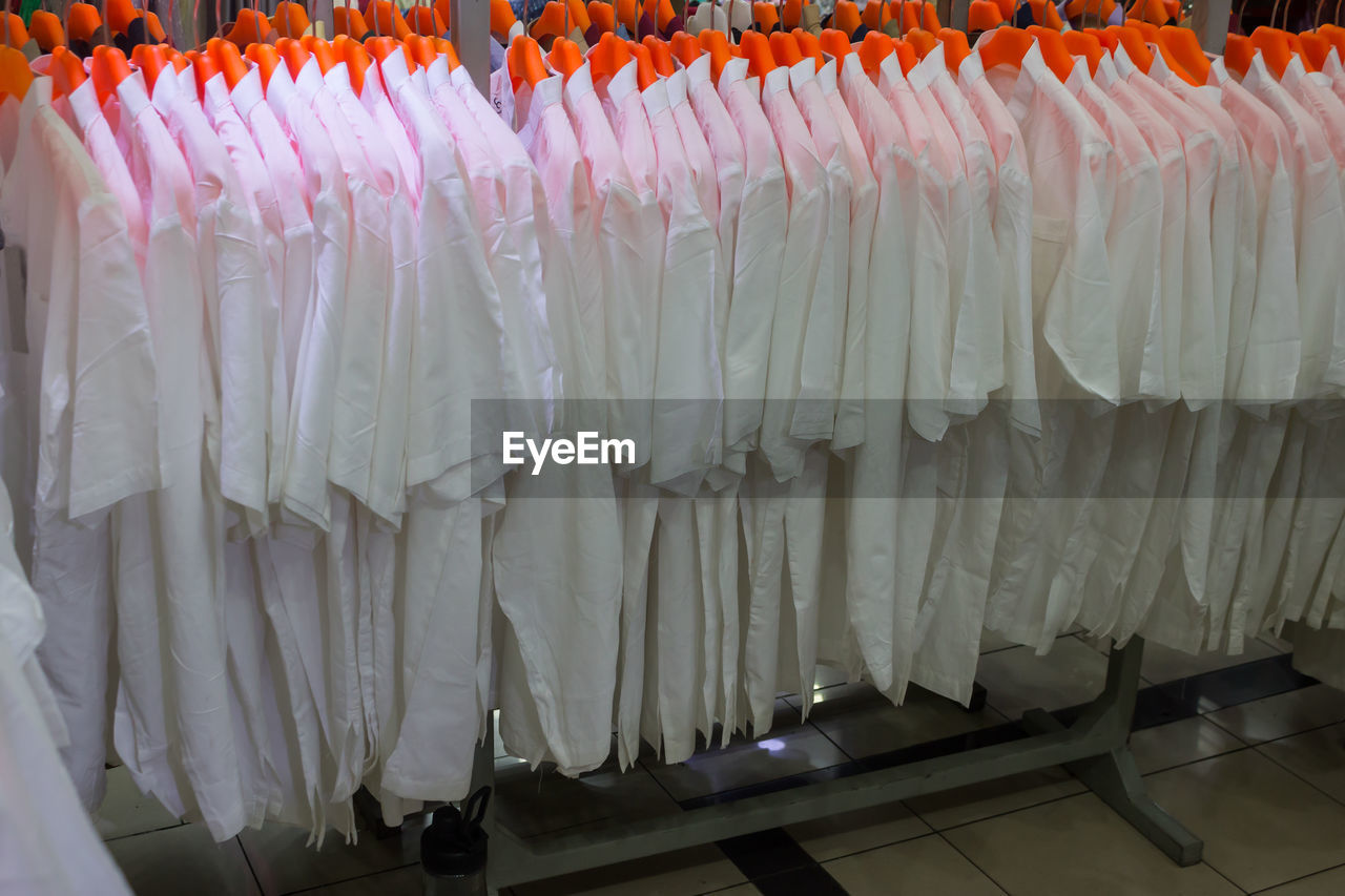 hanging, large group of objects, retail, in a row, no people, business, business finance and industry, abundance, white, for sale, store, indoors, order, market, textile, arrangement