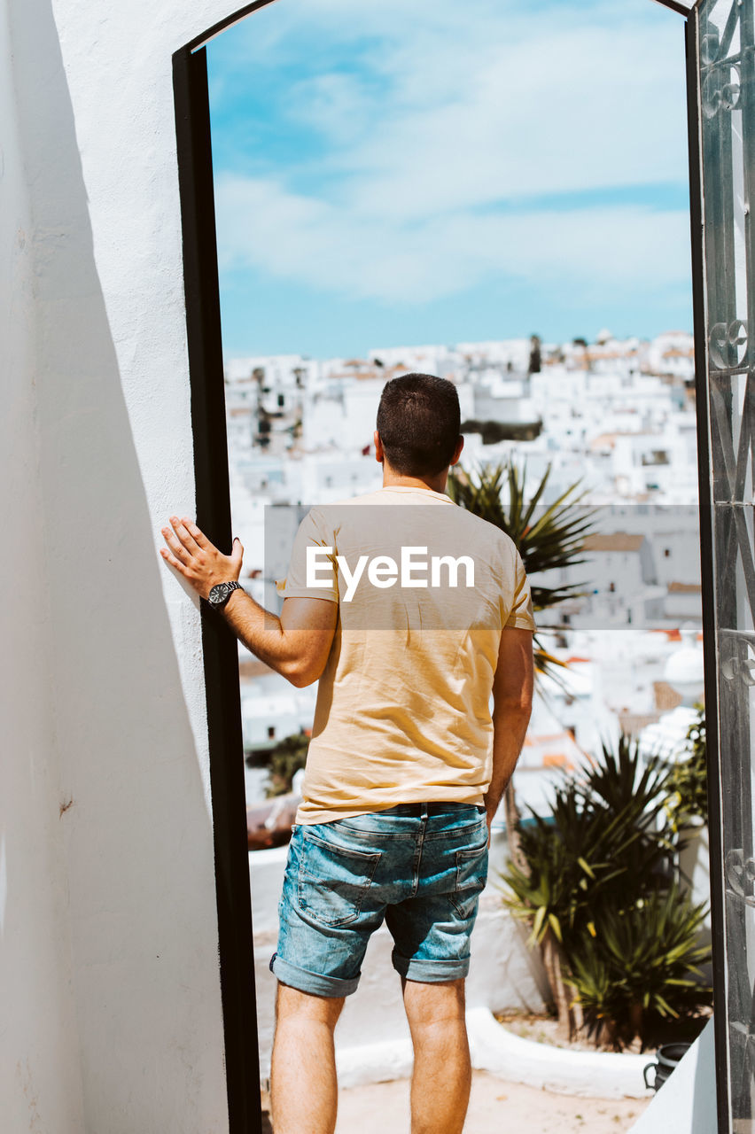 Young traveler looking through doorway over white spanish village