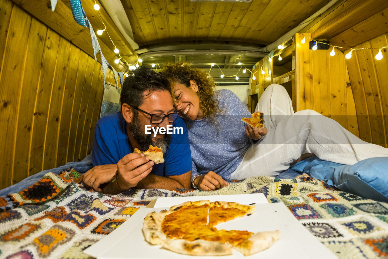 Couple enjoying pizza in illuminated room