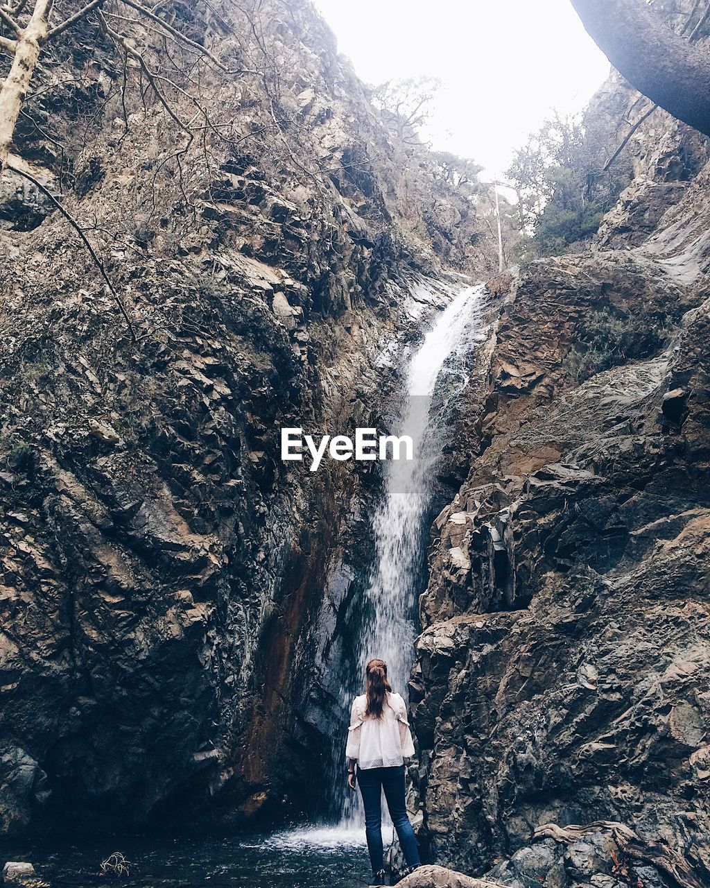 Rear view of woman looking at waterfall on mountain