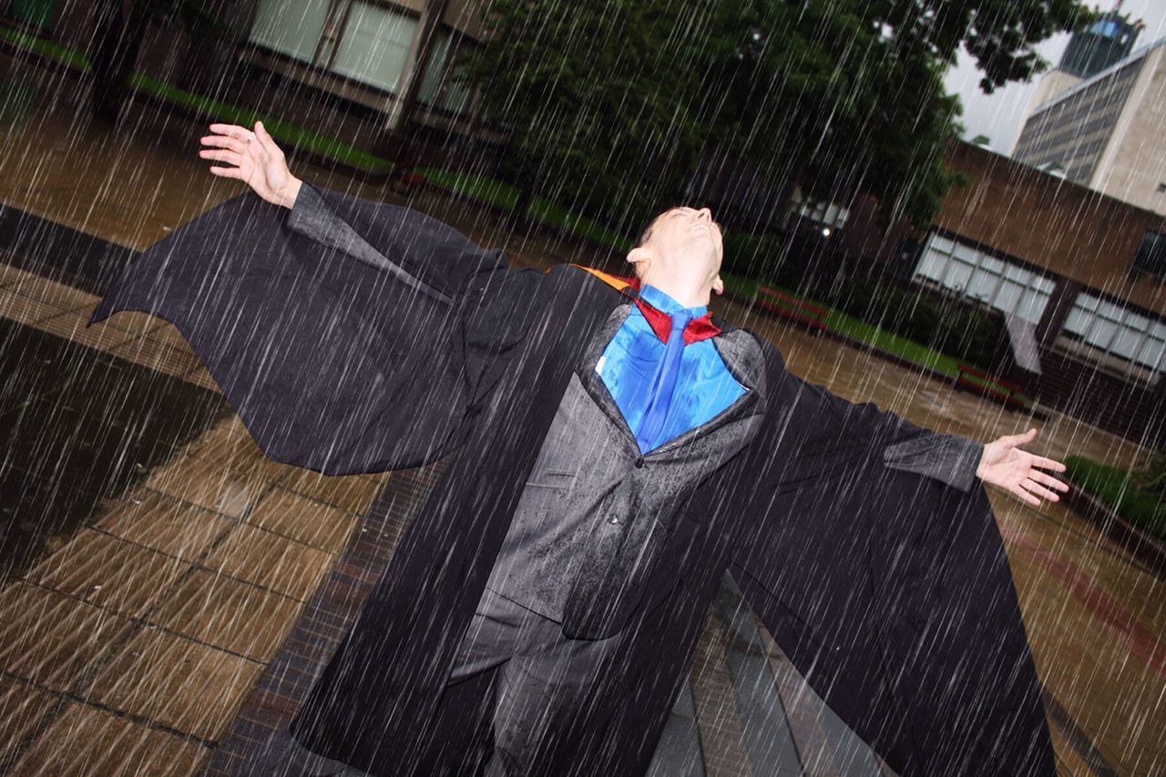 Young man enjoying rain at college campus