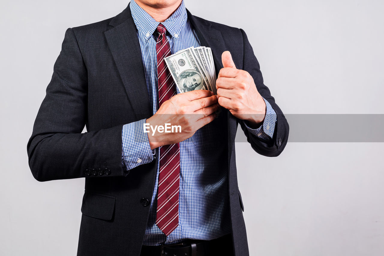 Businessman in suit holding several 100 dollar bills. finance concept.