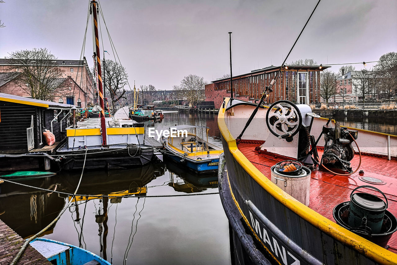 BOATS MOORED IN CANAL AGAINST SKY