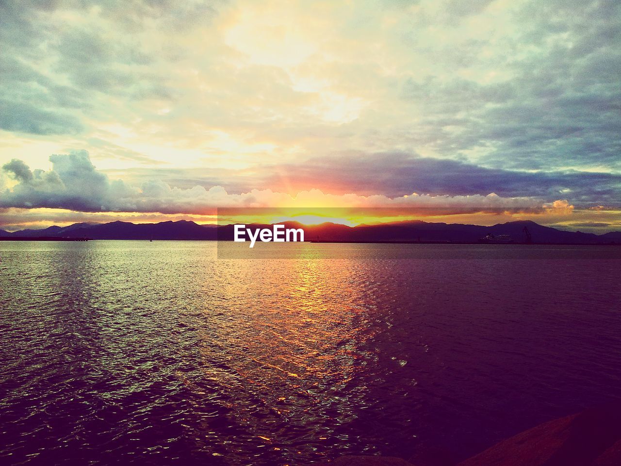 Scenic view of river against cloudy sky at sunset