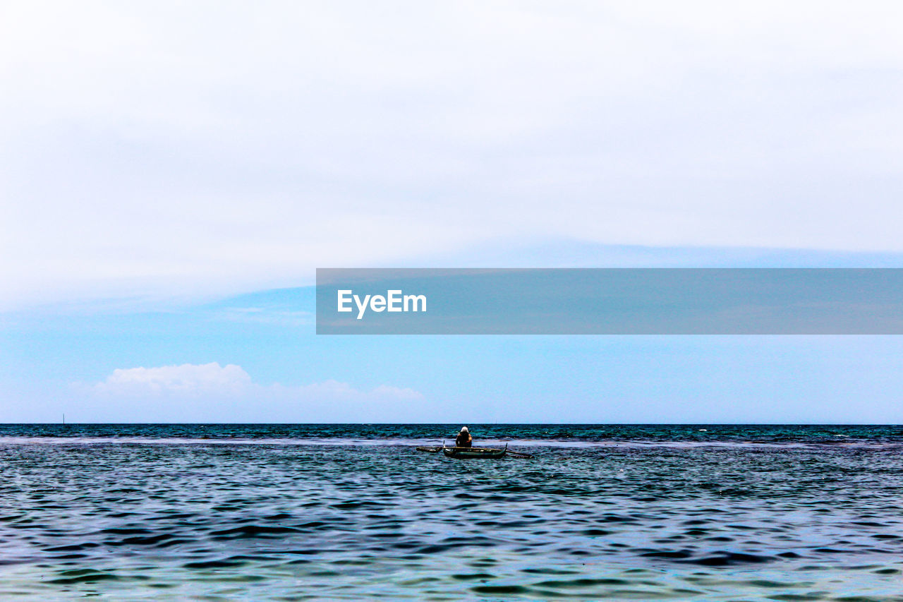 Person in boat at sea against sky