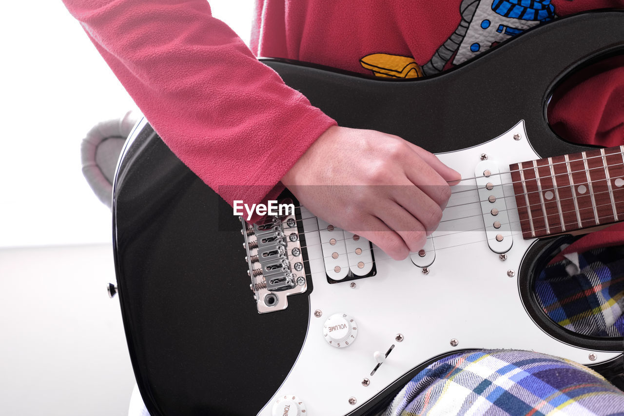 Close up of teen playing electric guitar at home during covid-19 pandemic lockdown. kids activities.