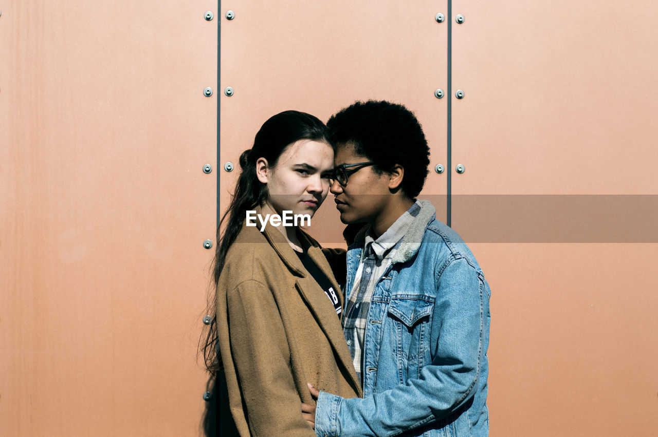 YOUNG COUPLE STANDING AGAINST WALL AT HOME