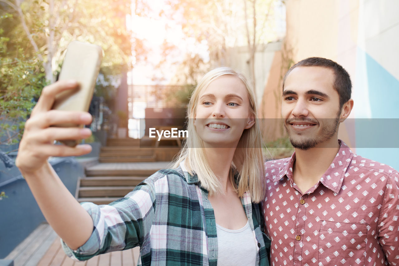 Smiling woman taking selfie with boyfriend