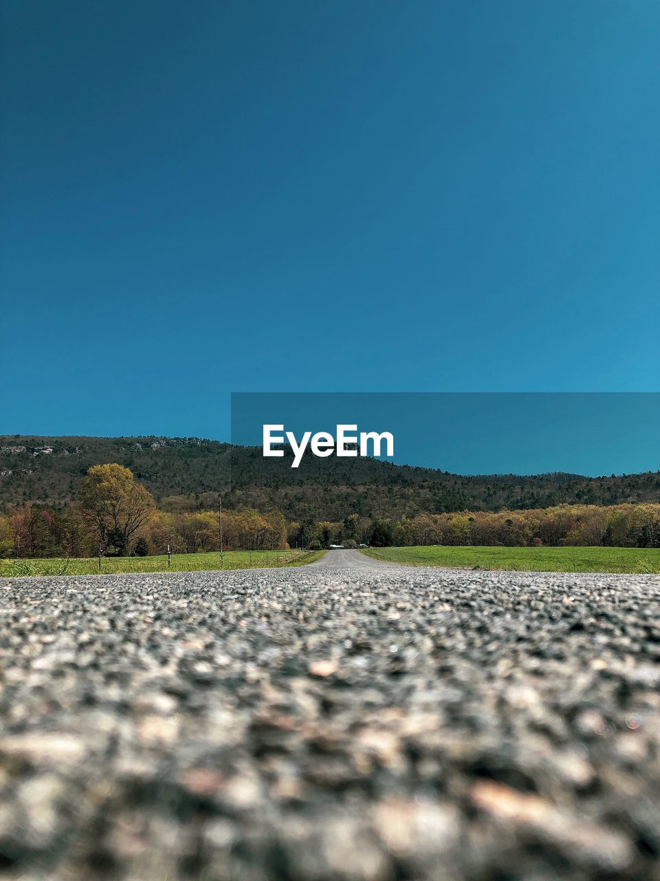 Surface level of road against clear blue sky