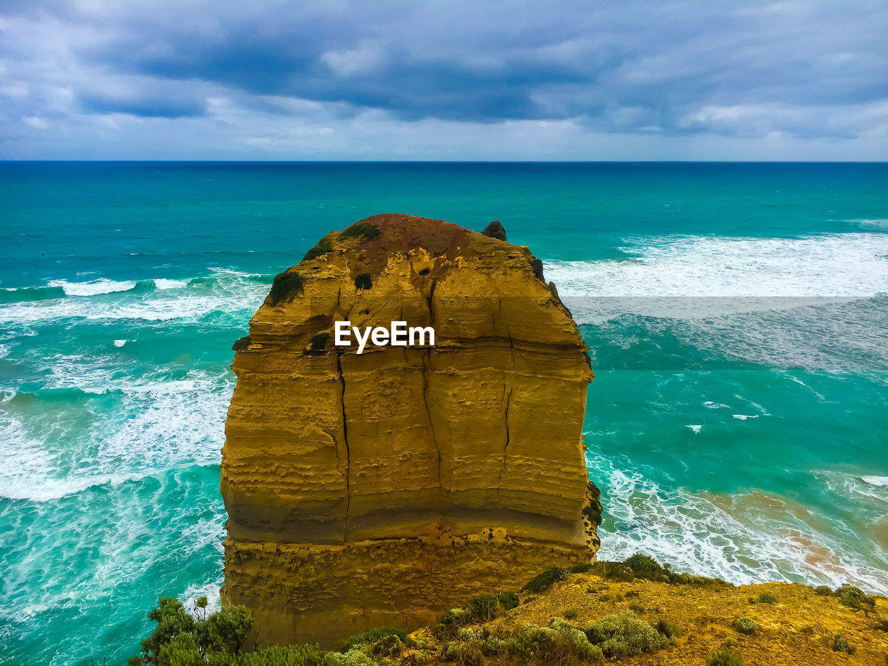 Scenic view of blue sea and waves against the cloudy sky