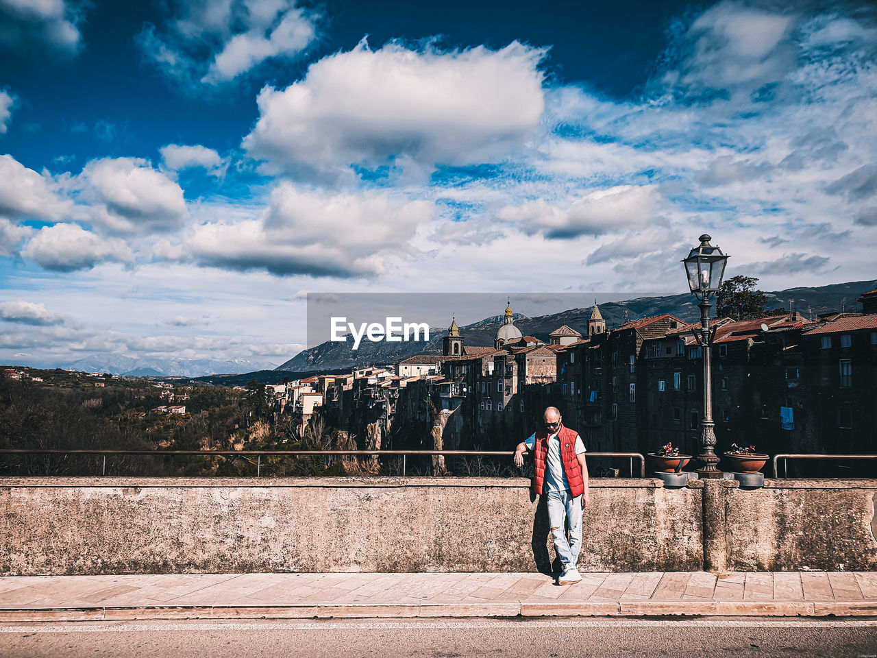 Rear view of people walking on street against sky