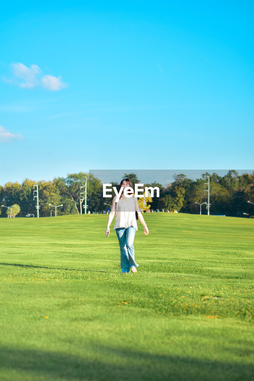 grass, leisure activity, sports, sky, golf, full length, golf course, adult, plant, activity, green, nature, casual clothing, copy space, men, day, weekend activities, lifestyles, sunlight, meadow, field, one person, golfer, player, green - golf course, lawn, tree, women, standing, emotion, enjoyment, outdoors, golf club, recreation, sunny, happiness, grassland, blue, motion, person, young adult, female, shadow