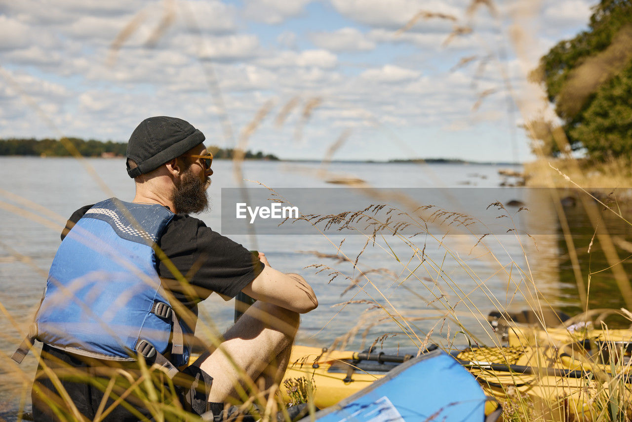 Man sitting and relaxing at lake near kayak