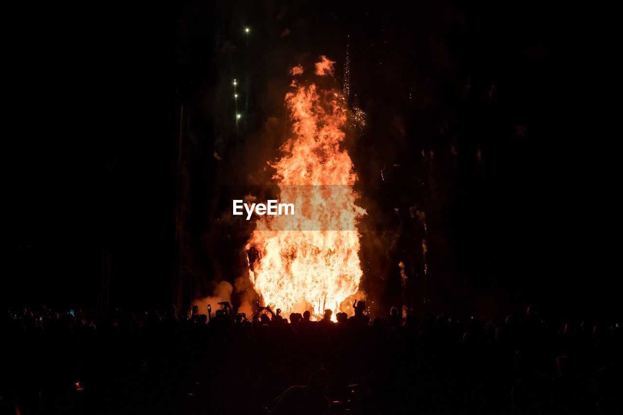 Silhouette people looking at fire during night