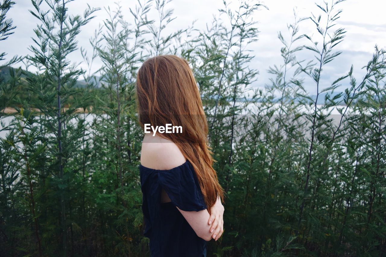 Side view of woman standing against plants