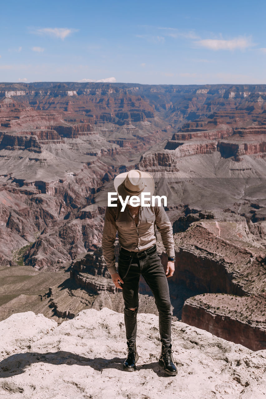 MAN STANDING ON ROCK AGAINST SKY